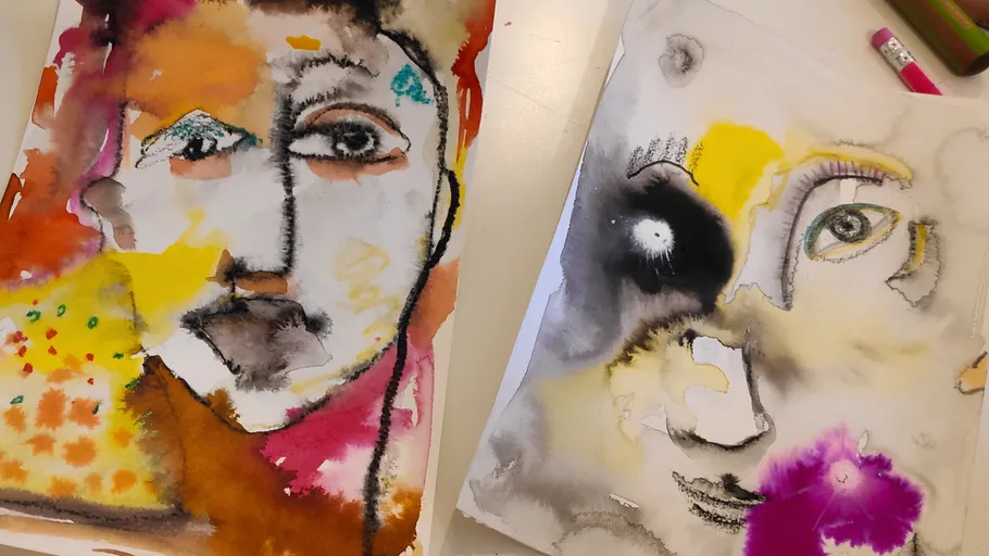 Two abstract face paintings on a table.