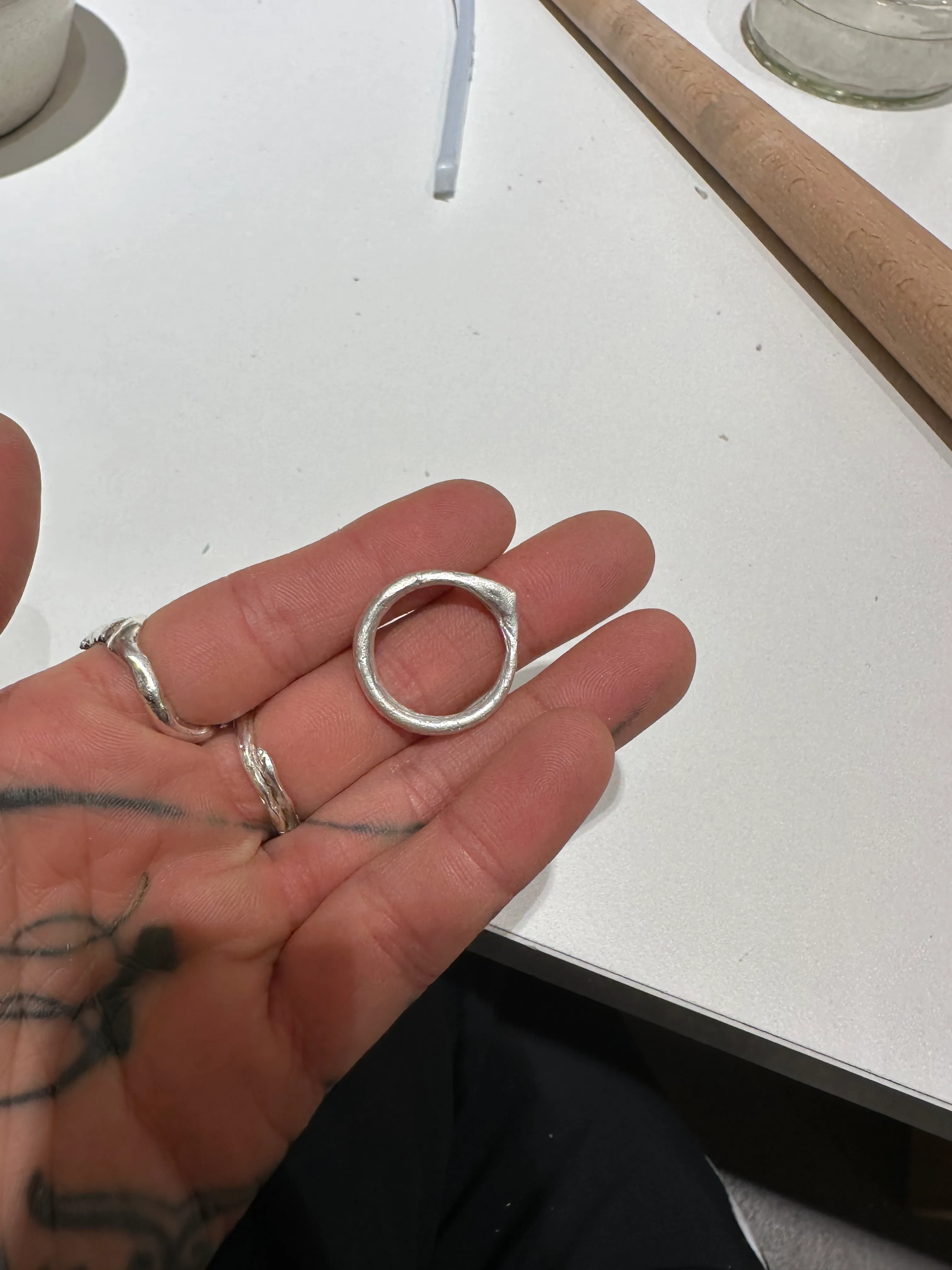 Hand hält silbernen Ring auf Tisch.