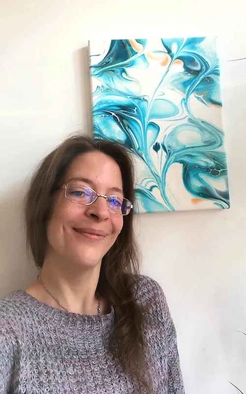 Lächelnde Person neben abstraktem blauem Gemälde.