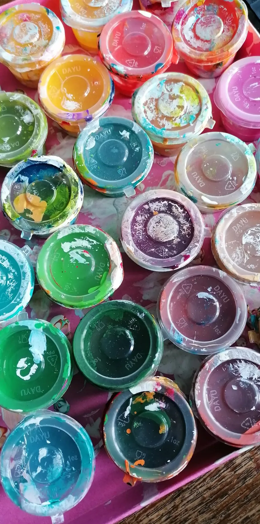 Colorful paint jars on a wooden table.