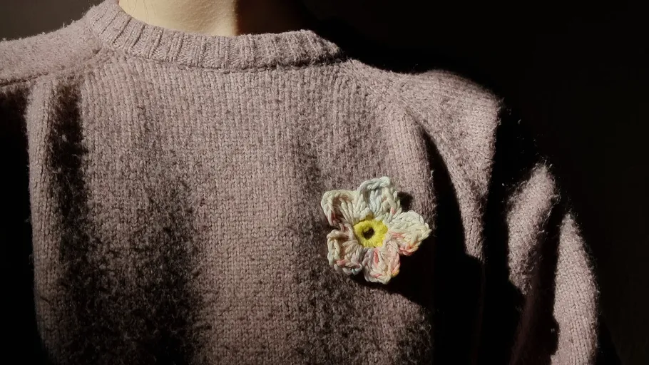 Blumenbrosche auf gestricktem Pullover im Schatten.