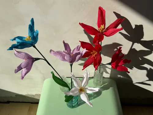Colorful paper flowers displayed in glass vases.