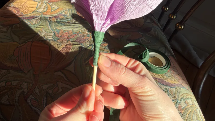 Hände wickeln lila Papierblume am Stiel.