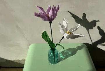 Paper flowers in a glass vase on table.