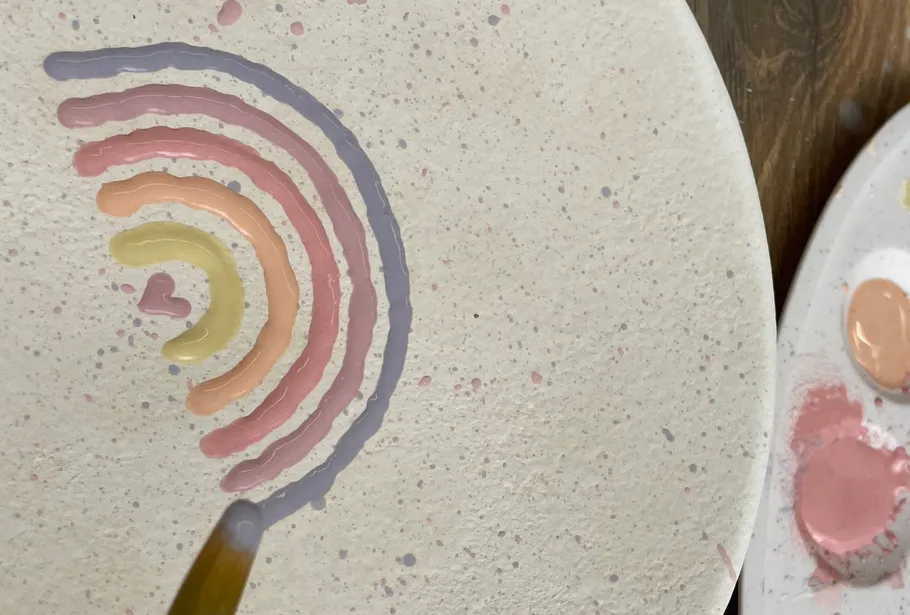 Painted rainbow on textured surface with brush.