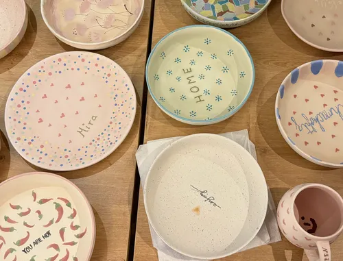 Bunte handgefertigte Teller und Becher auf Holztisch.