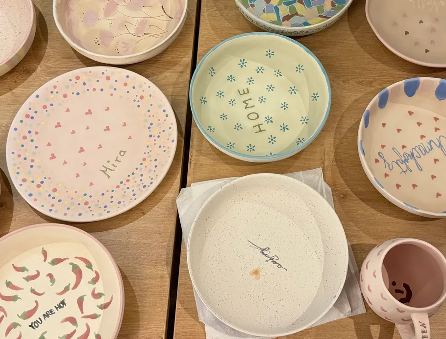 Bunte handgefertigte Teller und Becher auf Holztisch.