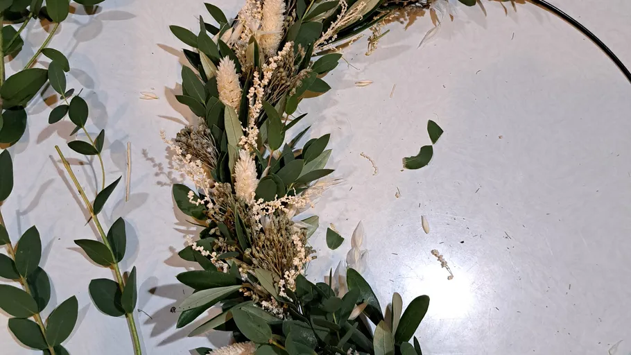 Floral wreath being crafted on table.