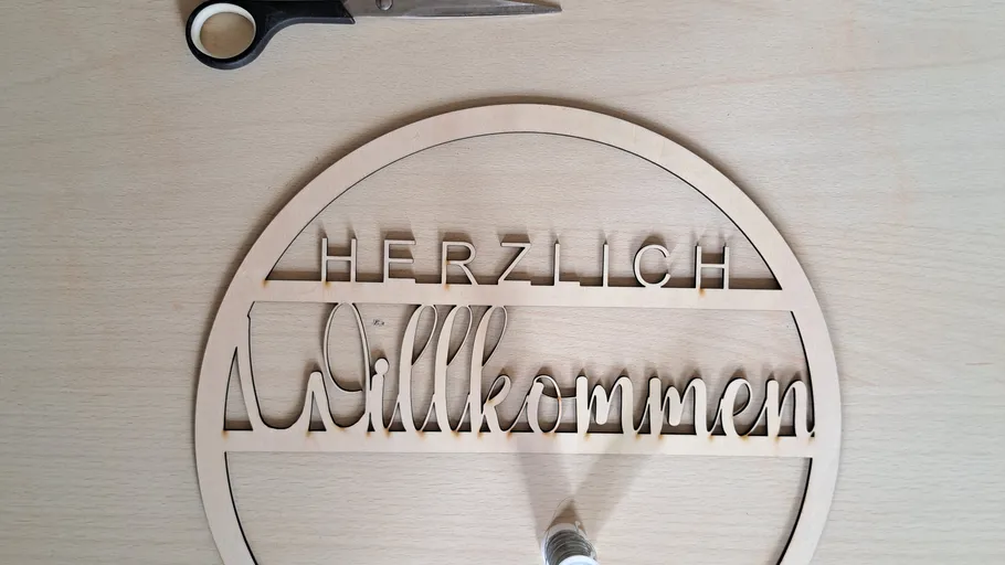 Wooden welcome sign on table, scissors nearby.