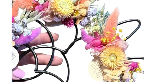 Hand hält Blumenstirnbänder mit bunten Blumen.