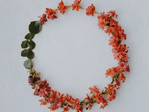 Circle of orange flowers hangs on the wall.