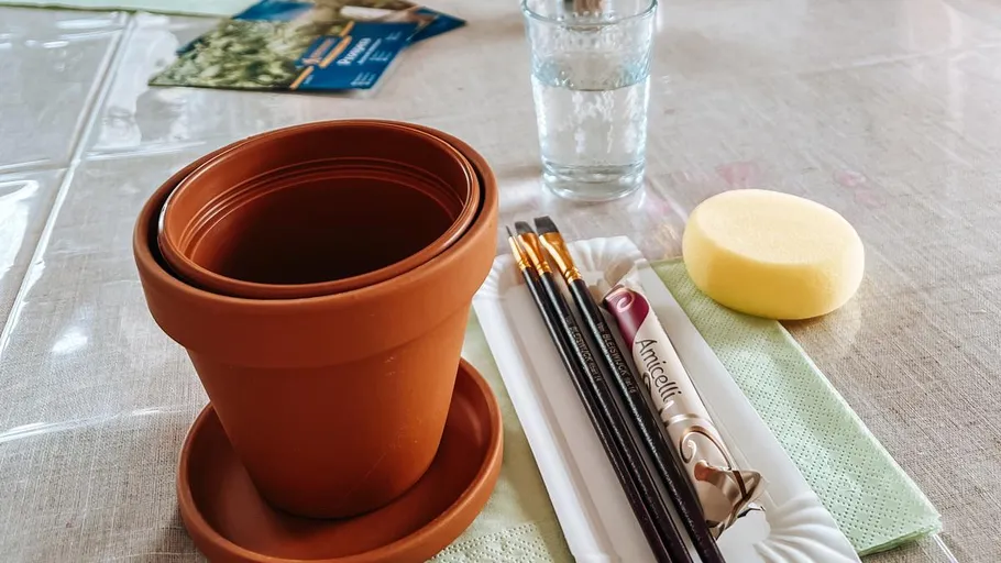 Tontopf und Malutensilien auf Tisch.