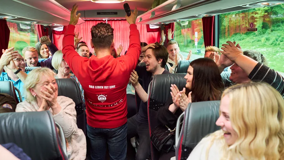 Person leading cheerful group on bus.