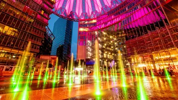 Bunte Brunnen unter beleuchteter Kuppel nachts.