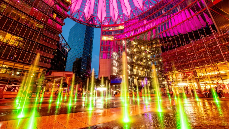 Colorful fountains under illuminated dome at night.