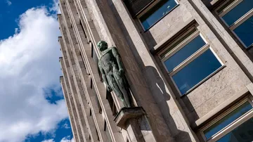 Statue on building facade under blue sky.