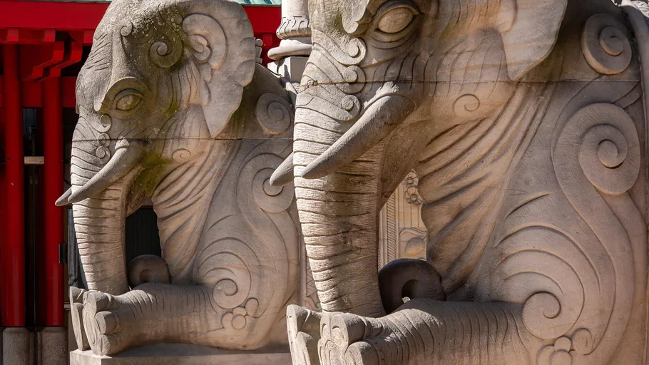 Stone elephant sculptures near red structure.