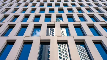 Geometrische Gebäudefassade mit reflektierenden Fenstern.