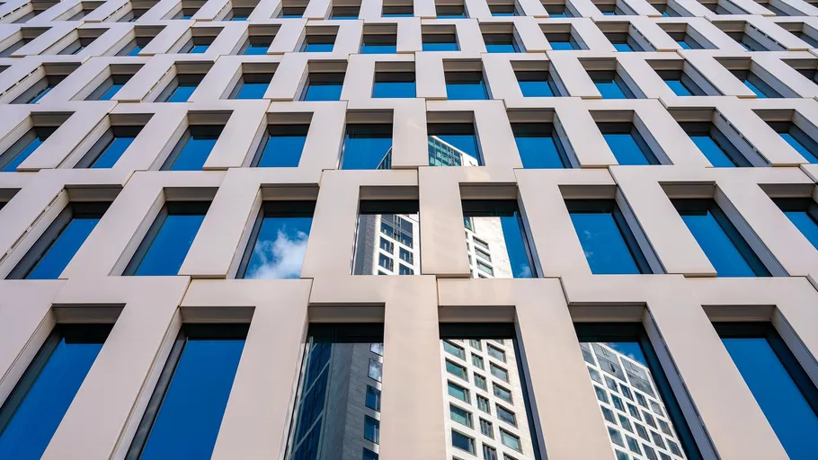 Geometrische Gebäudefassade mit reflektierenden Fenstern.