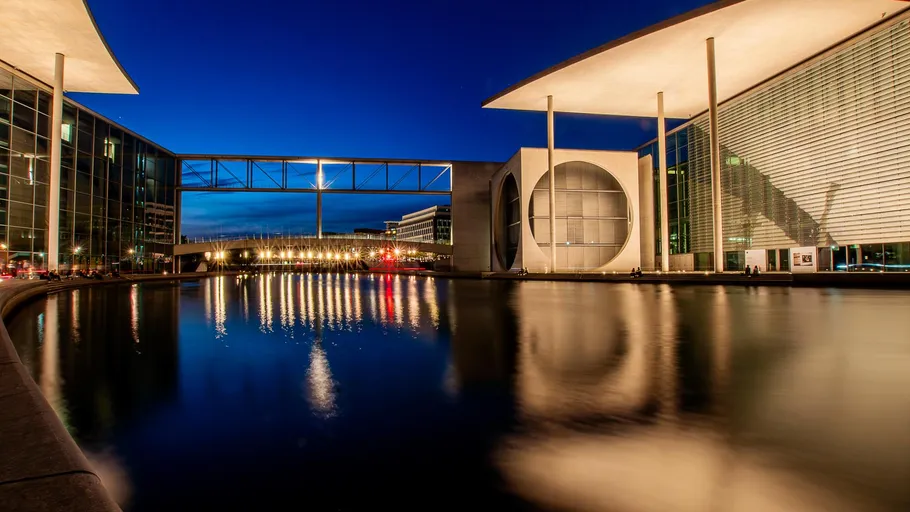 Modern buildings reflecting in river at dusk.