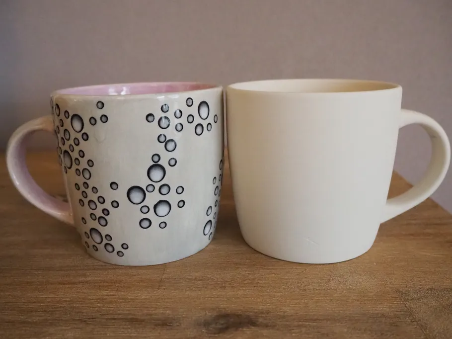 Two cups stand on a wooden background.