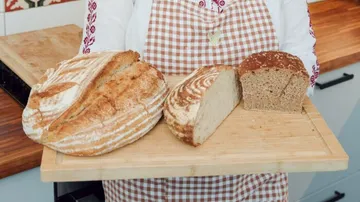 Person hält Holzbrett mit Brotleiben.