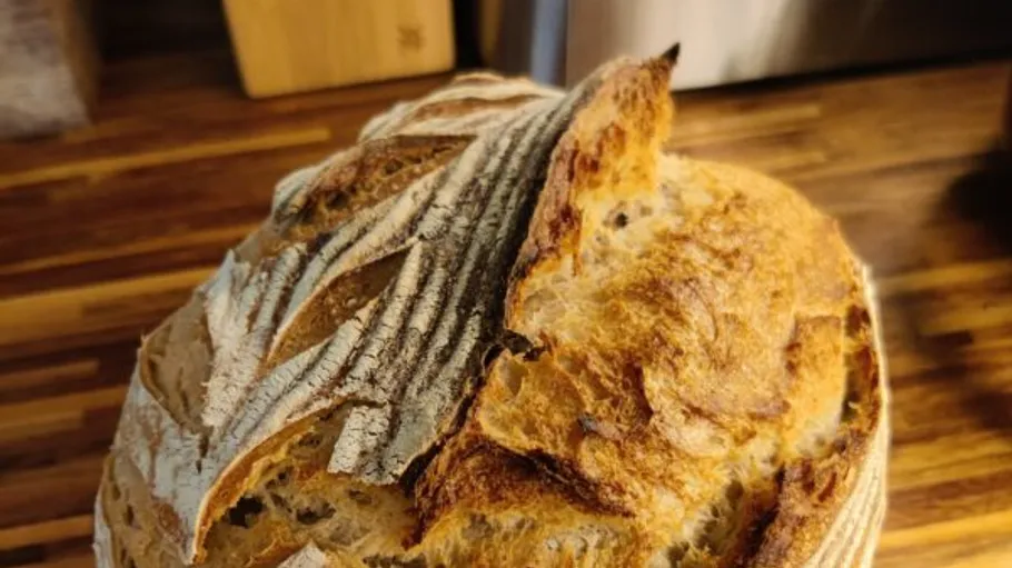 Crusty loaf of sourdough bread on table.