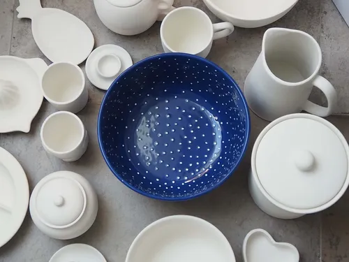 Colourful bowl surrounded by white crockery on a table.