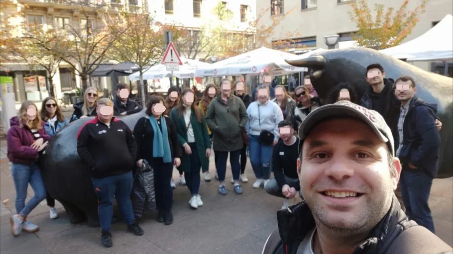Group posing near statues in outdoor plaza.