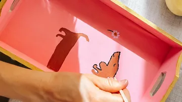 Hand malt Hundefiguren auf rosa Tablett.