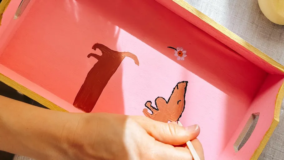 Hand painting dog figures on pink tray.