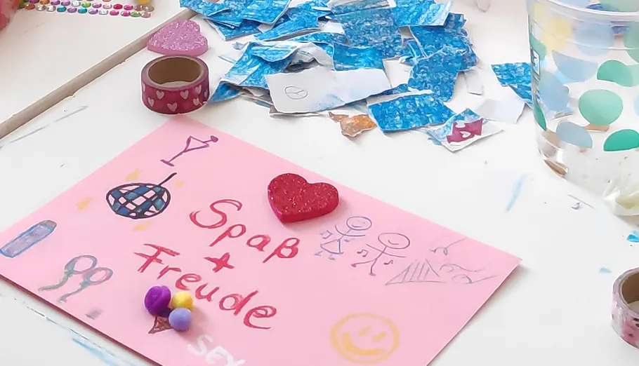 Bastelmaterialien und dekorierte rosa Karte auf Tisch.