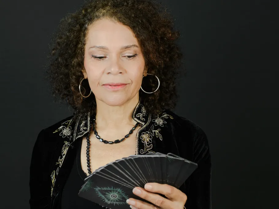 Woman reading tarot cards, dark background.