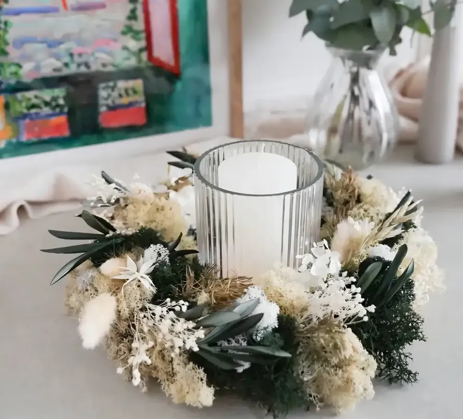 Candle in glass holder with floral wreath.