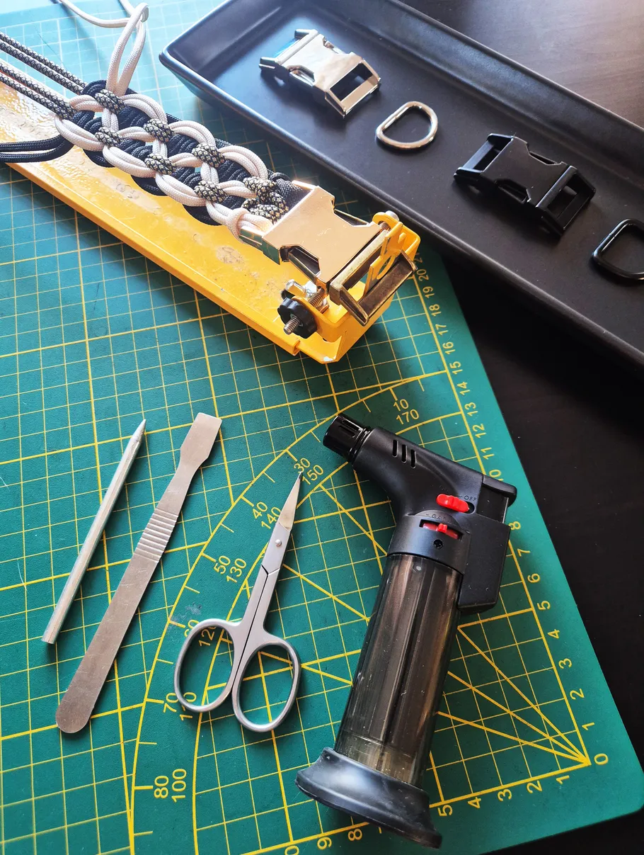 Paracord bracelet making tools on cutting mat.