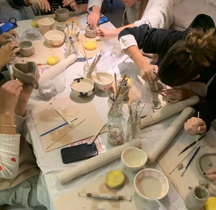 People crafting pottery at a table workshop.