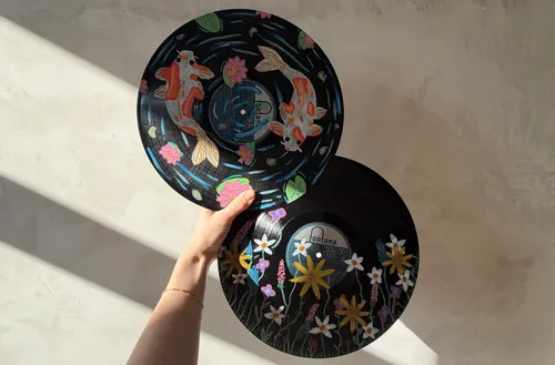 Hand hält zwei bemalte Schallplatten.