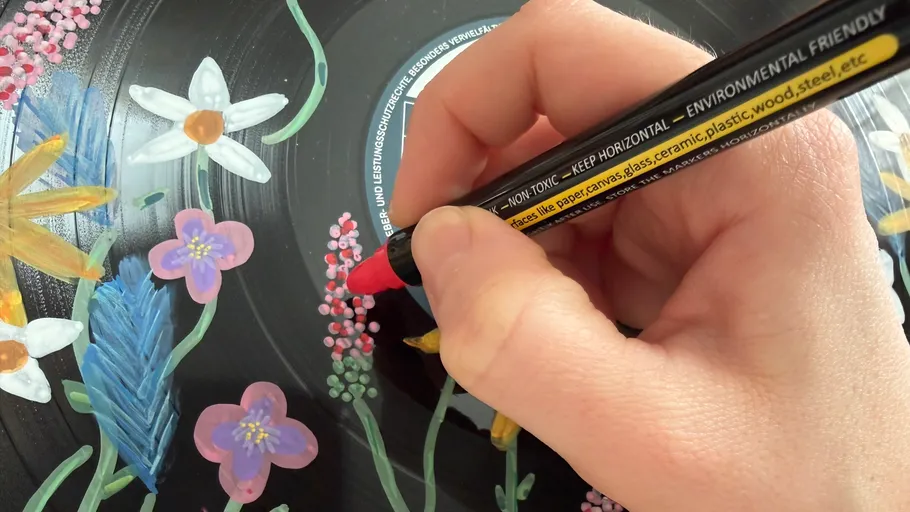 Hand painting flowers on black vinyl record.