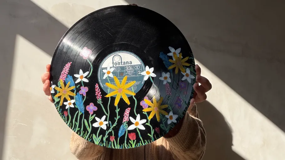 Person hält bemalte Schallplatte mit Blumen.
