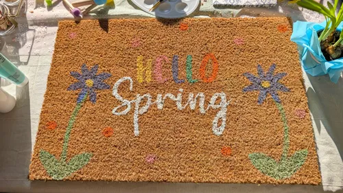 Decorative doormat with 'Hello Spring' and flowers.