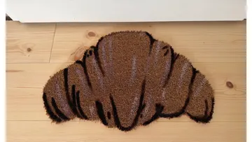 Croissant-shaped doormat on wooden floor.