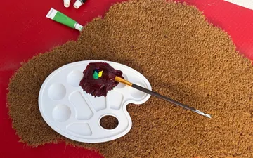 Palette mit Pinsel auf strukturiertem Untergrund.