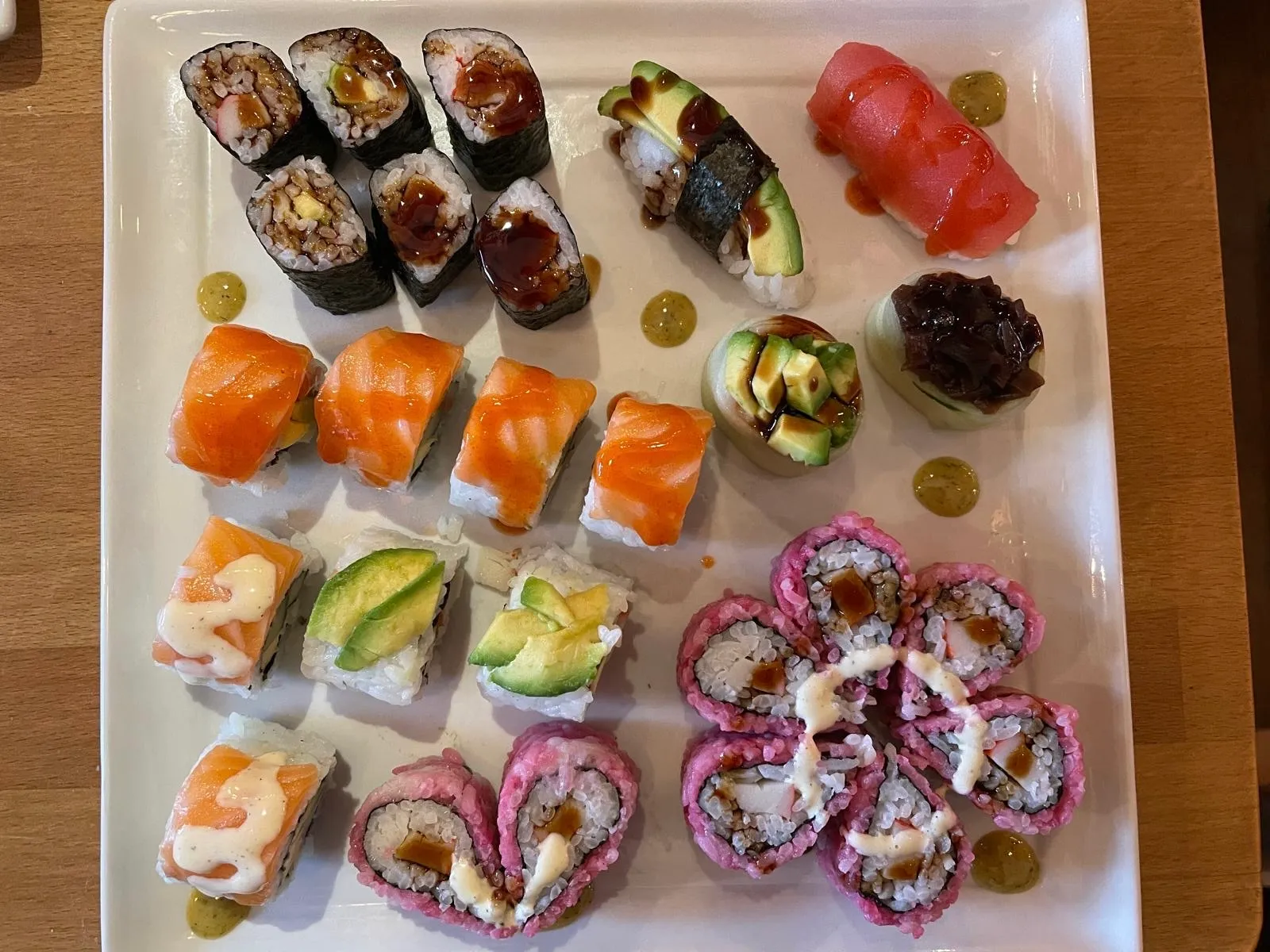 Verschiedene Sushi-Rollen auf einem rechteckigen Teller.