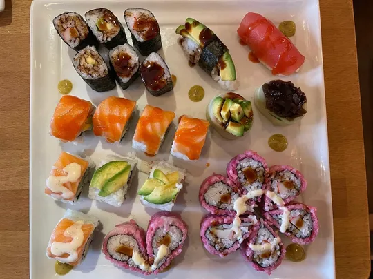 Verschiedene Sushi-Rollen auf einem rechteckigen Teller.