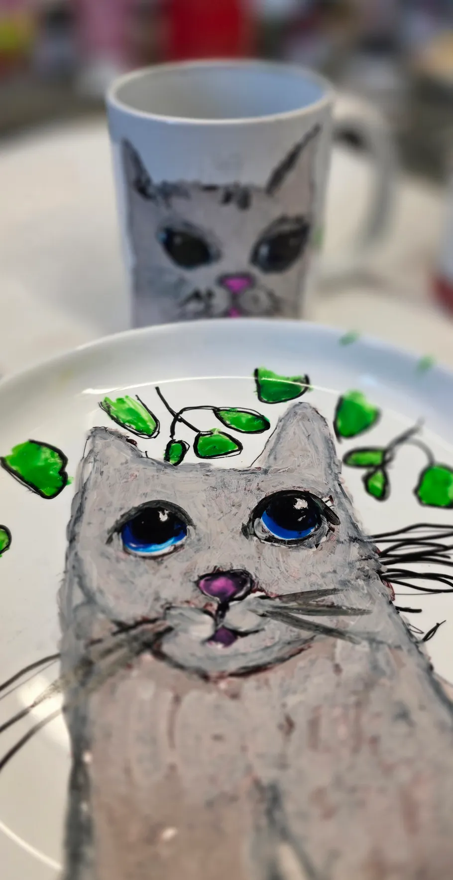 Gemalter Katze auf Teller mit passender Tasse.
