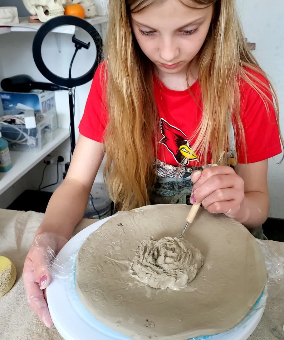 Girl sculpting clay on a table, art studio.