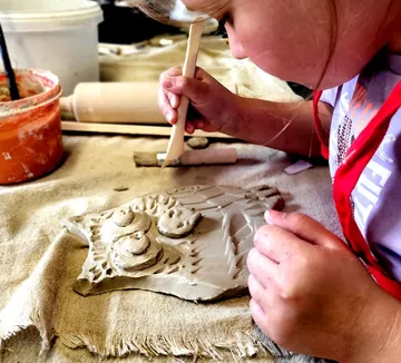 Child sculpting clay owl on cloth.