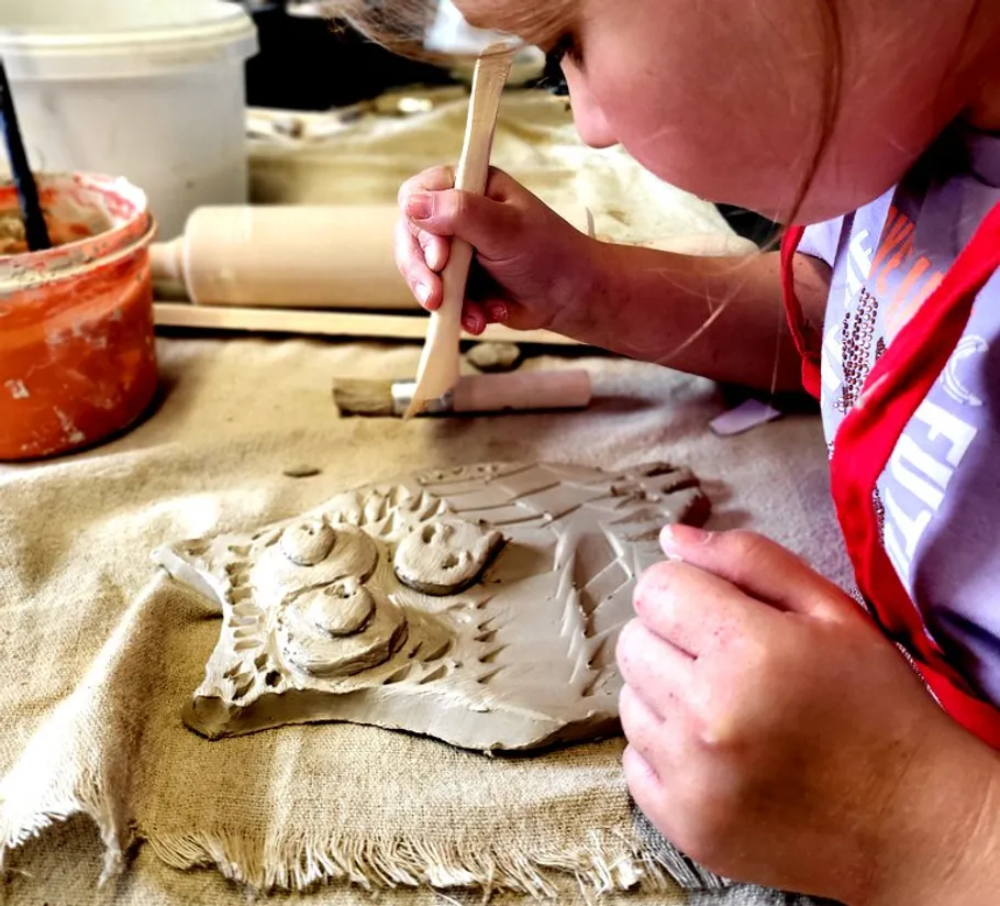 Child sculpting clay owl on cloth.