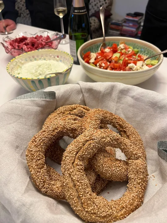 Sesam-Brezeln auf Tisch mit Salaten.