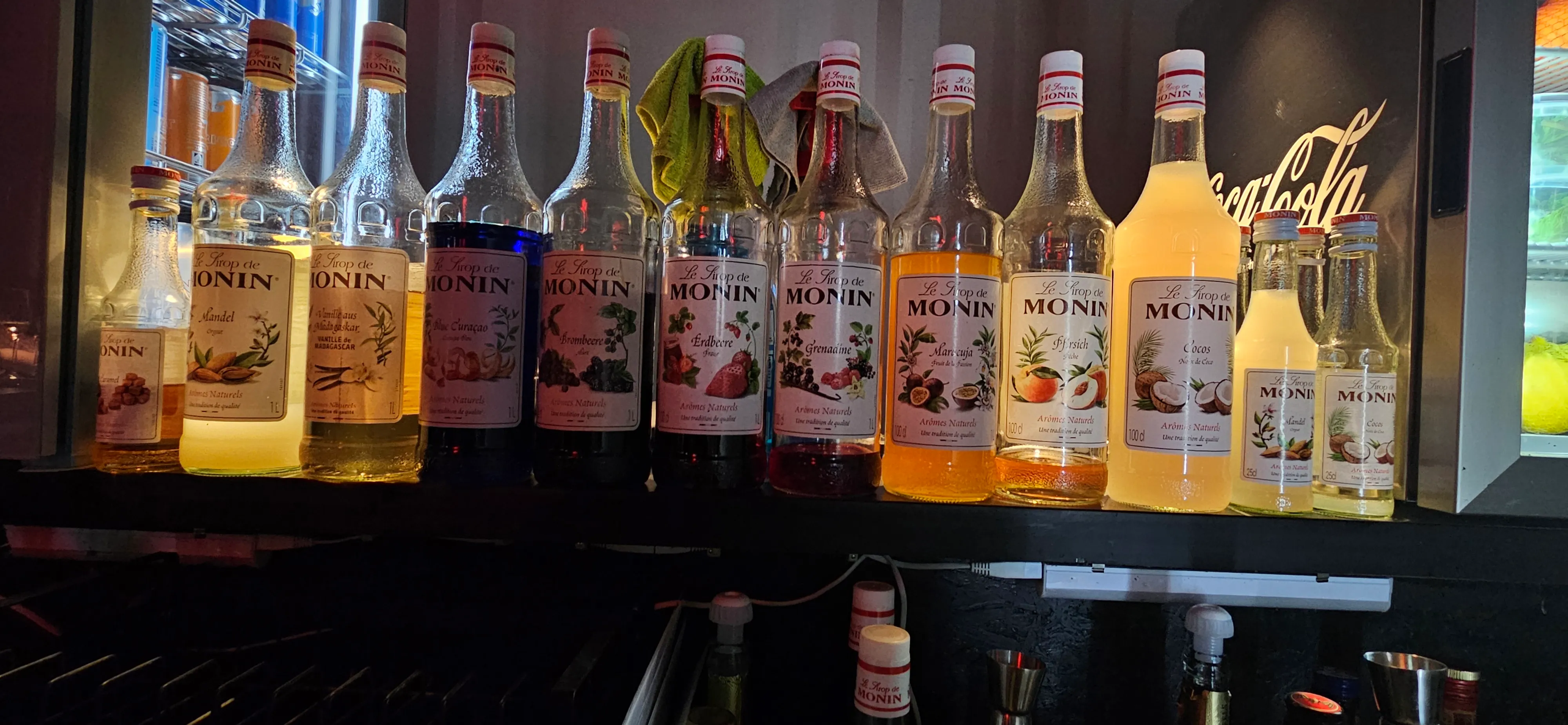 Verschiedene Monin-Sirupflaschen in einer Bar ausgestellt.